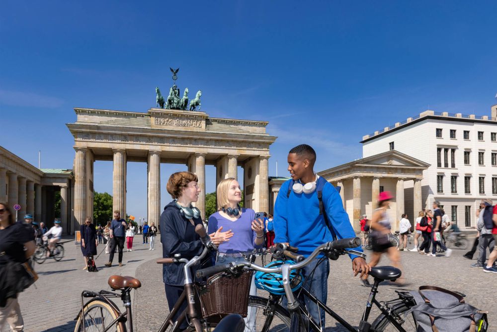 Personen mit Fahrrädern vor dem Brandenburger Tor.