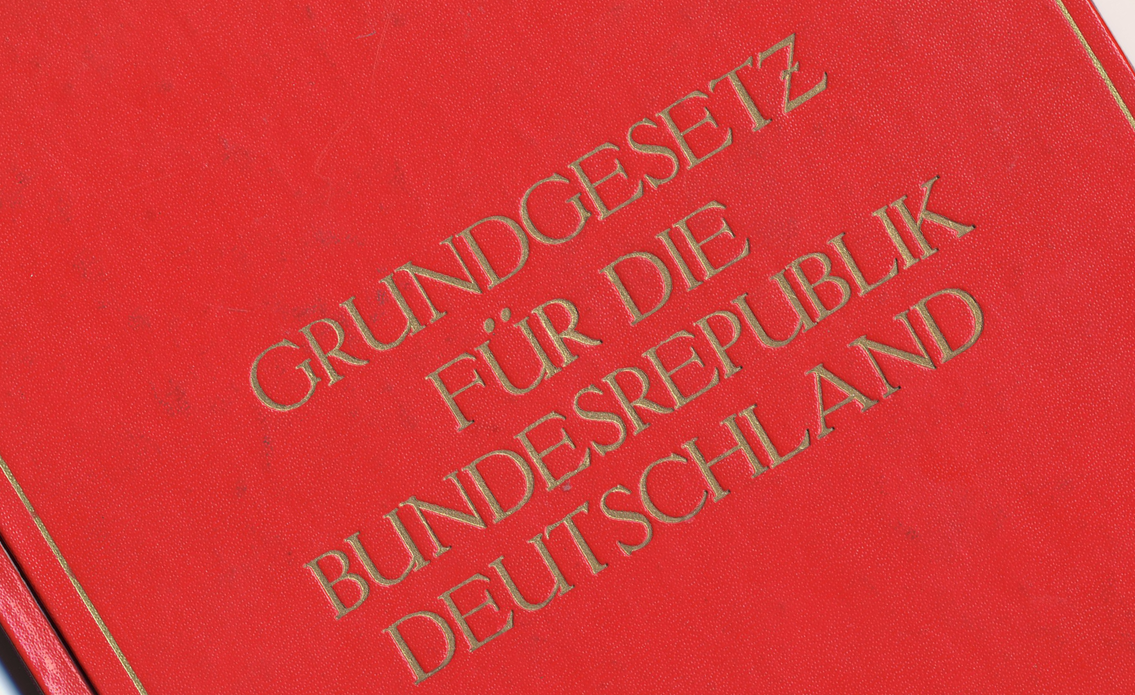 Rotes Buchcover, auf dem in goldener Schrift steht: Grundgesetz für die Bundesrepublik Deutschland.