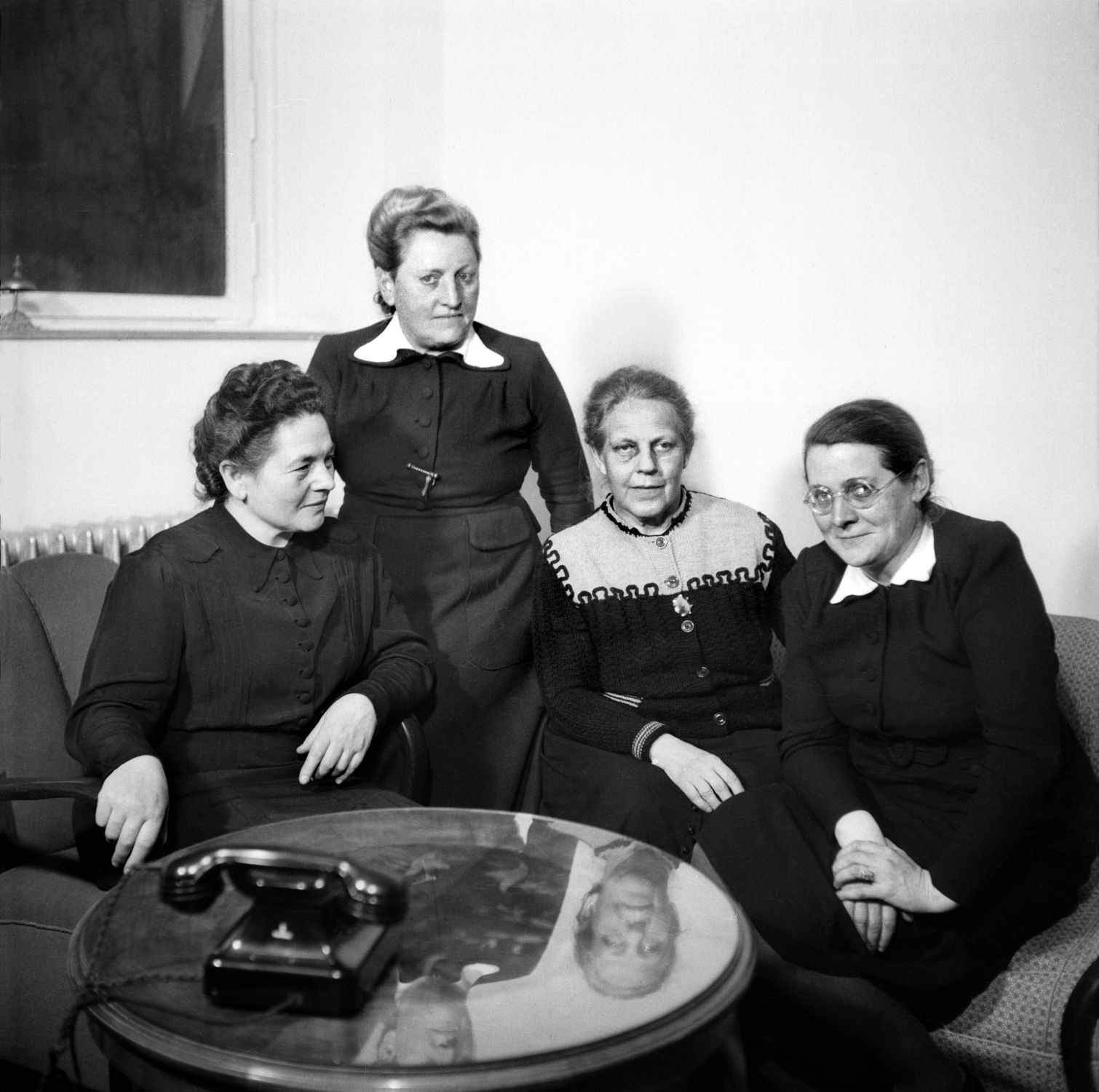 Auf dem Foto sitzen Friederike Nadig, Elisabeth Selbert, Helene Weber und Helene Wessel nebenaneinander. Sie tragen dunkle Kleider und Hochsteckfrisuren. 