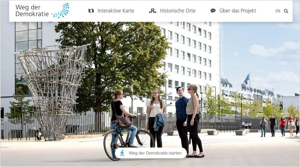 Screenshot der Webseite zum Weg der Demokratie mit einem großen Foto von Menschen auf dem Platz der Vereinten Nationen in Bonn