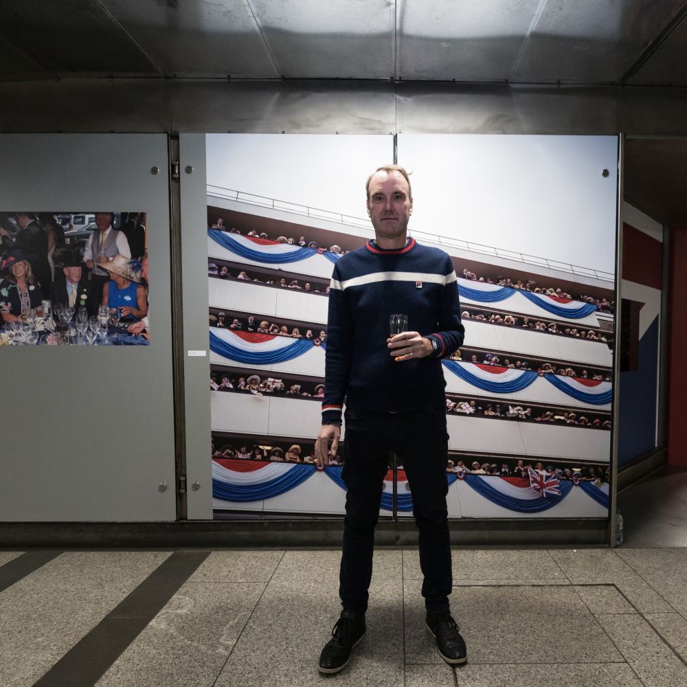 Full body photo of the artist in front of his pictures