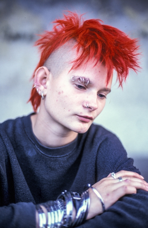 Ein junger, männlicher Punk mit rotgefärbten Haaren.