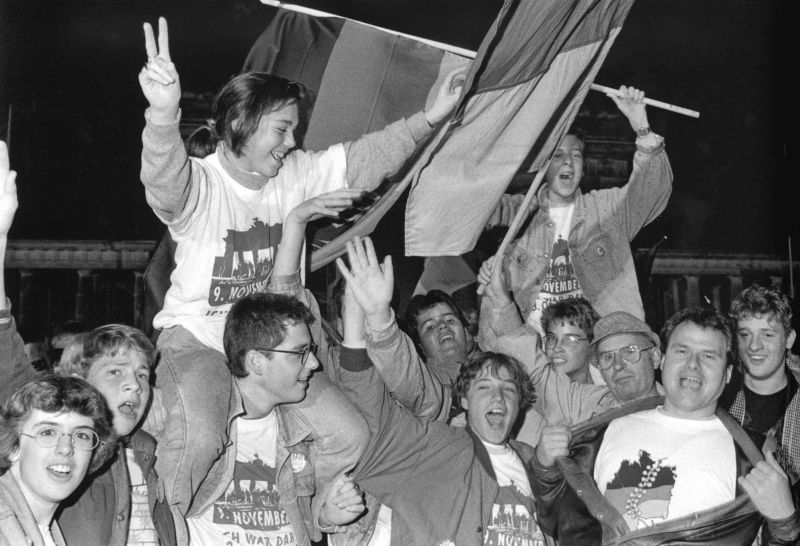 Jubelnde Menschen mit Deutschlandfahnen und T-Shirts mit dem Brandenburger Tor darauf.