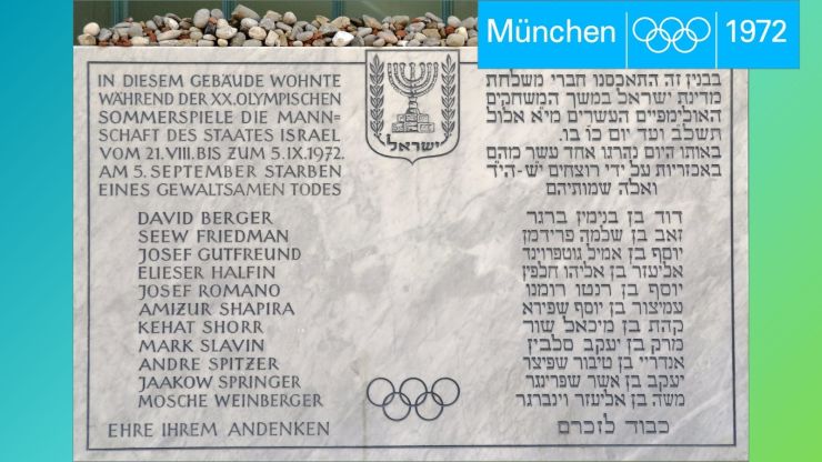 Fotografie der Gedenktafel der Opfer des Attentats und Teile des blauen Olympia 1972-Logos