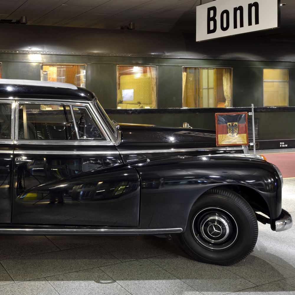 Konrad Adenauer's Mercedes Benz in the foreground and a train compartment.