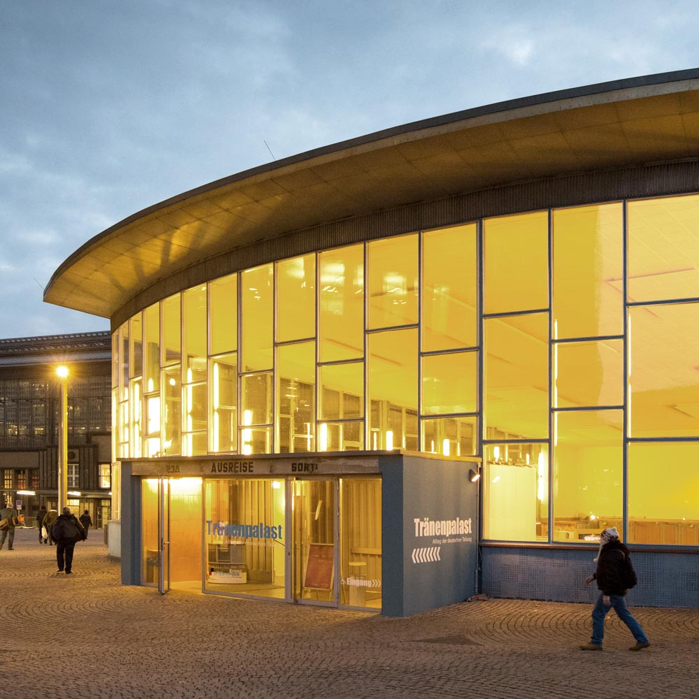 Der Tränenpalast ist ein Gebäude mit einer großen, von innen erleuchteten Fensterglasfront. Der Sockel ist blau gefliest. das Flachdach leicht gebogen. Es gibt einen kleinen rechteckigen Vorbau.