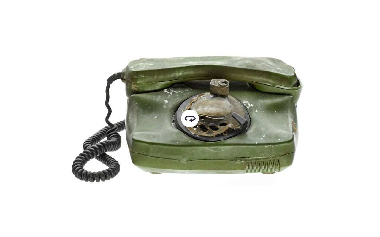 Grünes Telefon mit Wählscheibe, Schloss und Brandspuren. 
