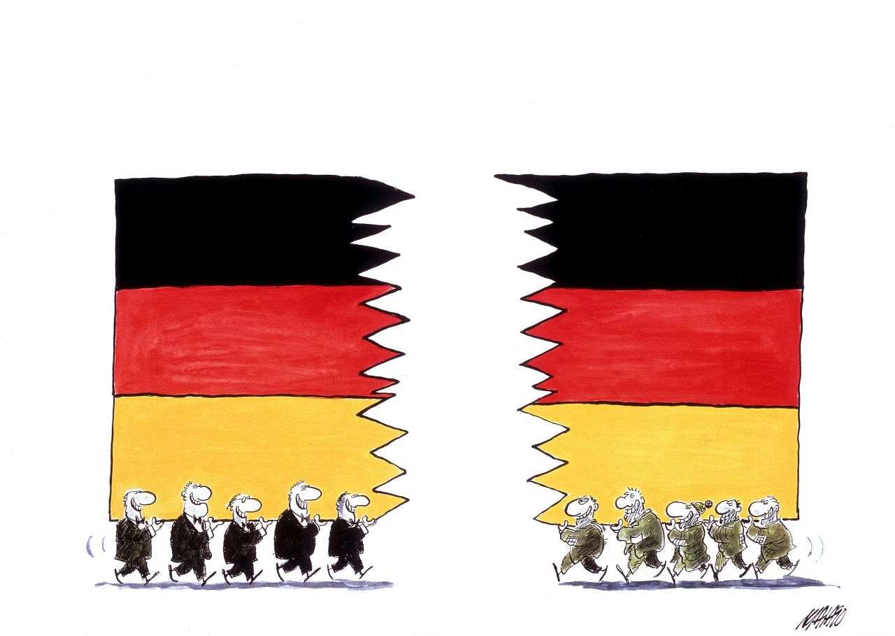Karikatur von Maia: Ostdeutsche und Westdeutsche tragen jeweils eine zerrissene Hälfte einer deutschen Flagge aufeinander zu.