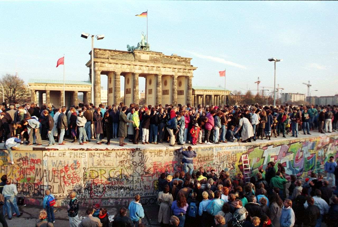 Menschen besteigen die Berliner Mauer vor dem Brandenburger Tor am 10. November 1989.