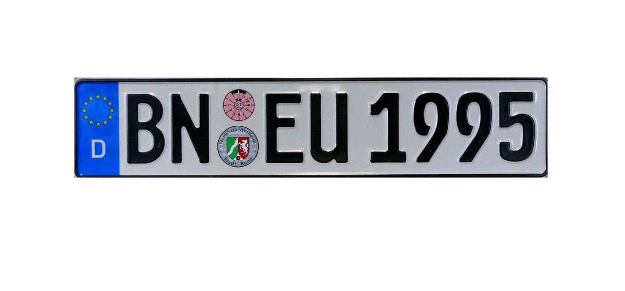 Weißes Nummernschild mit erhabener schwarzer Umrandung. Erhabene schwarze Buchstaben und Zahlen: BN EU 1995. Zwischen BN und EU oben rosafarbene Prüfplakette. Darunter graue Zulassungsplakette der Stadt Bonn mit Wappen von Nordrhein-Westfalen. Links blaues Band mit zwölf gelben Sternen der europäischen Flagge, darunter in weiß: D.