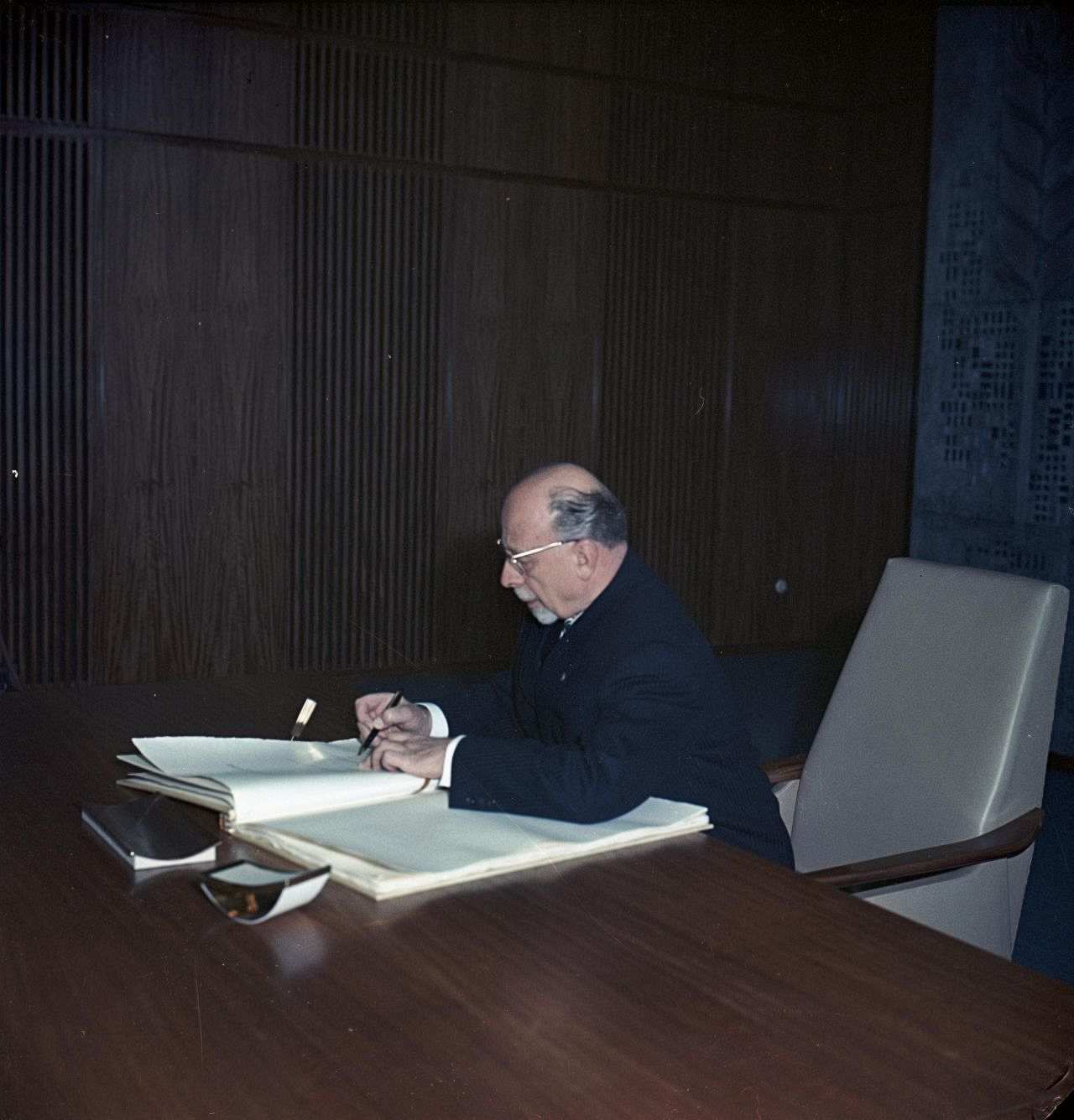 Walter Ulbricht sitzt an einem Schreibtisch und unterschreibt ein Dokument, die Verfassung der DDR.