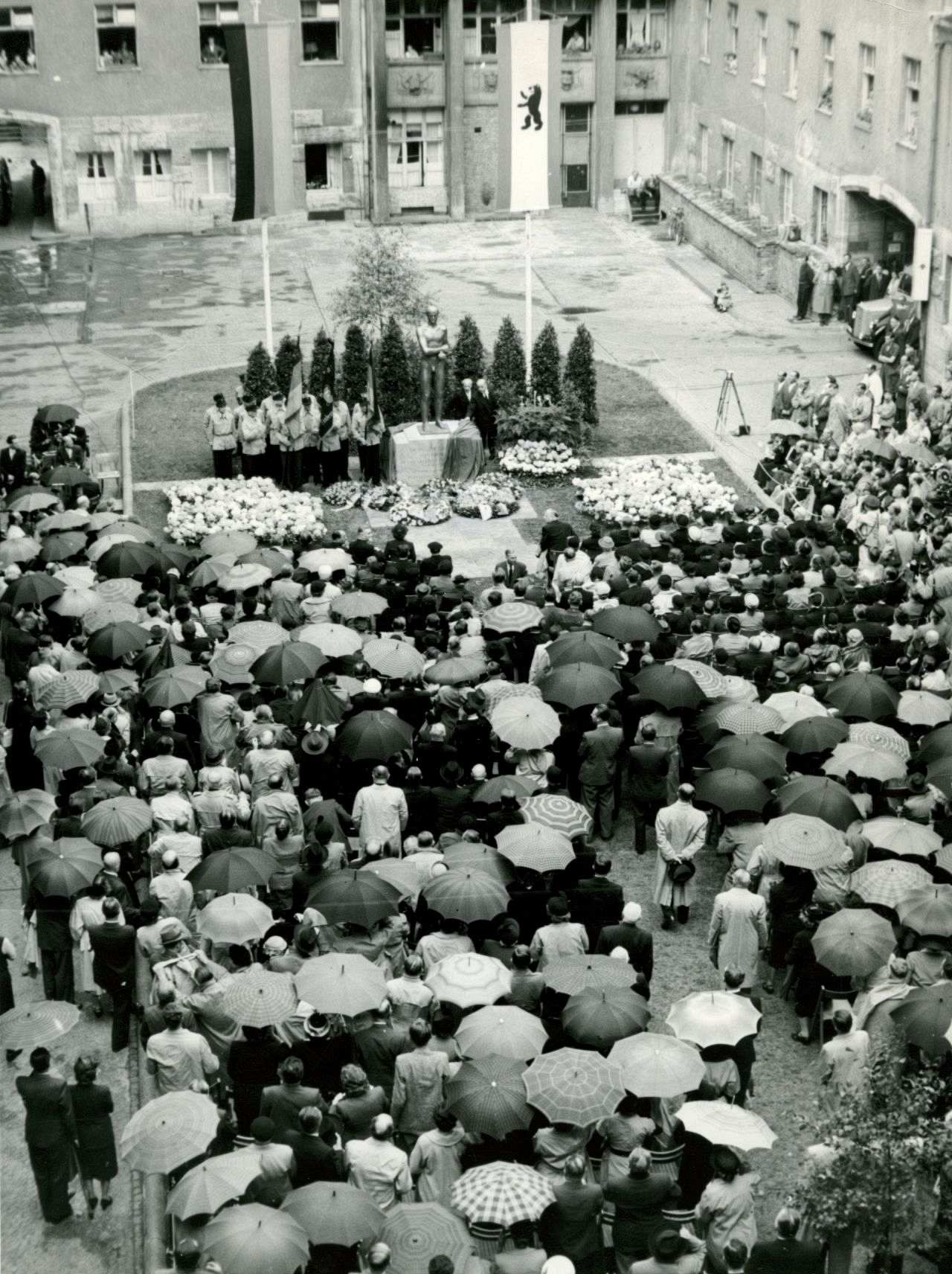 Menschenmenge vielfach mit Regenschirmen vor dem enthüllten Denkmal für die Opfer des 20. Juli 1944 im Hof des ehemaligen Reichskriegsministeriums im Berliner Bendlerblock.