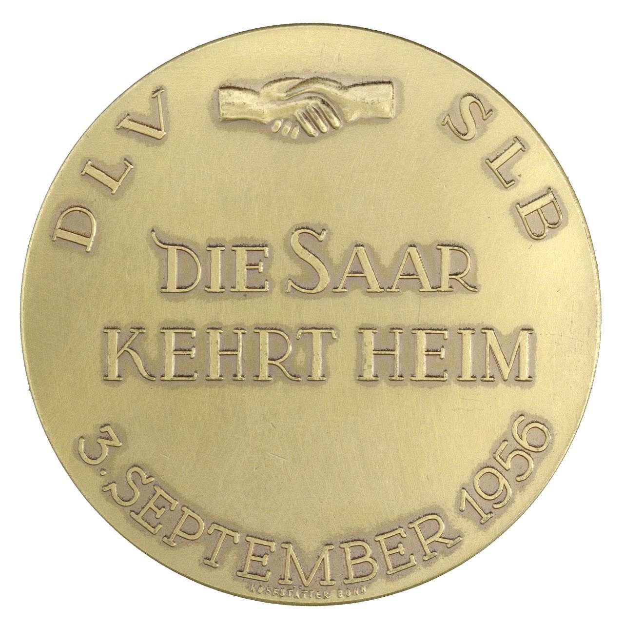 Auf der Vorderseite erhabene Umschrift 'DLV SLB 3. September 1956'. Zwischen DLV und SLB zwei schüttelnde Hände. In der Mitte erhaben in Großbuchstaben 'Die Saar kehrt heim'.