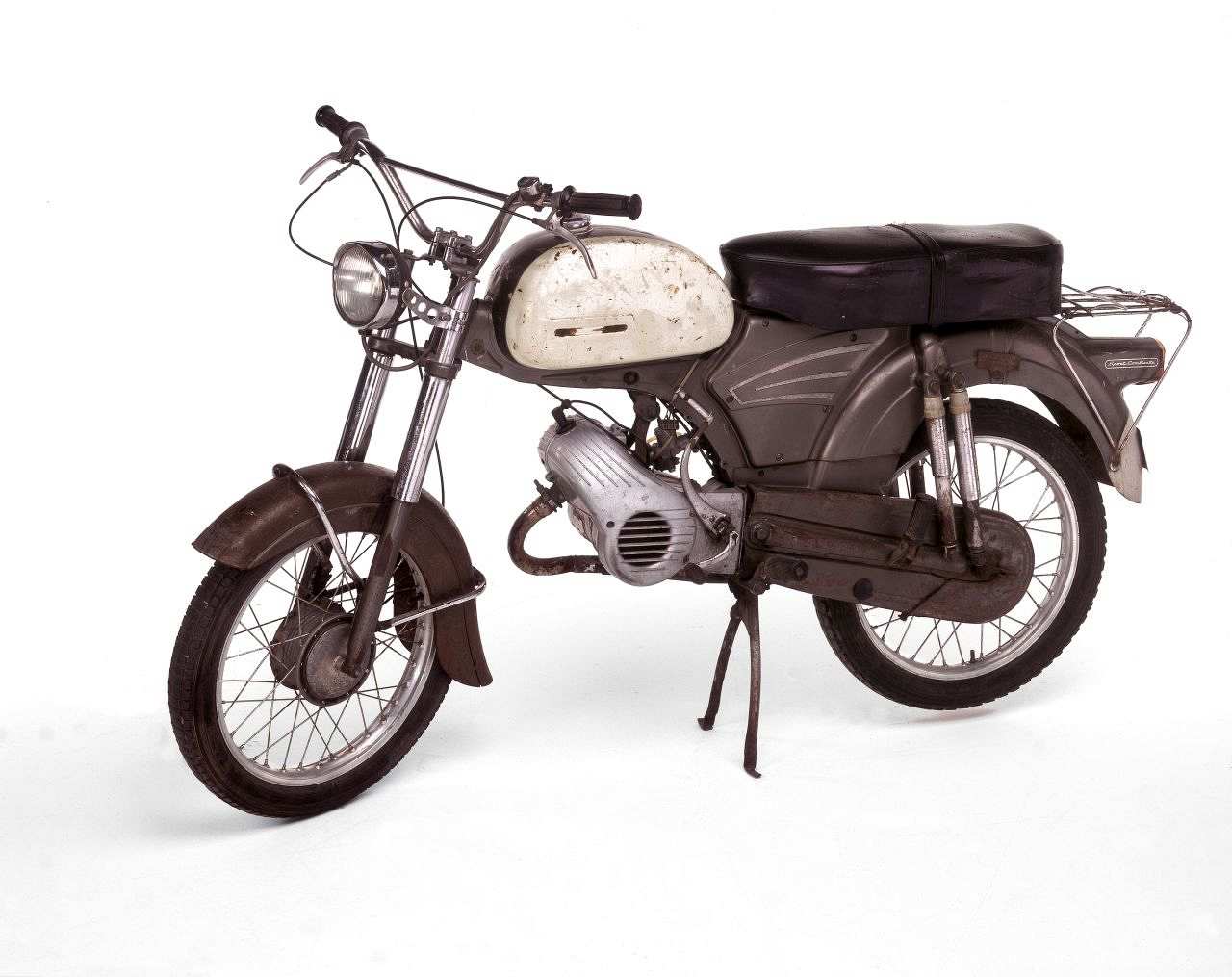 Metallgraues Moped, silberfarbene Motorverkleidung, weißer Tank mit grauem Mittelstreifen. Schwarze Doppelsitzbank, Kickstarter links, Kettenkasten, Mittelständer, hinten Stoßdämpfer, Speichenräder, Crosslenker, runder Scheinwerfer. Hinten Gepäckträger.