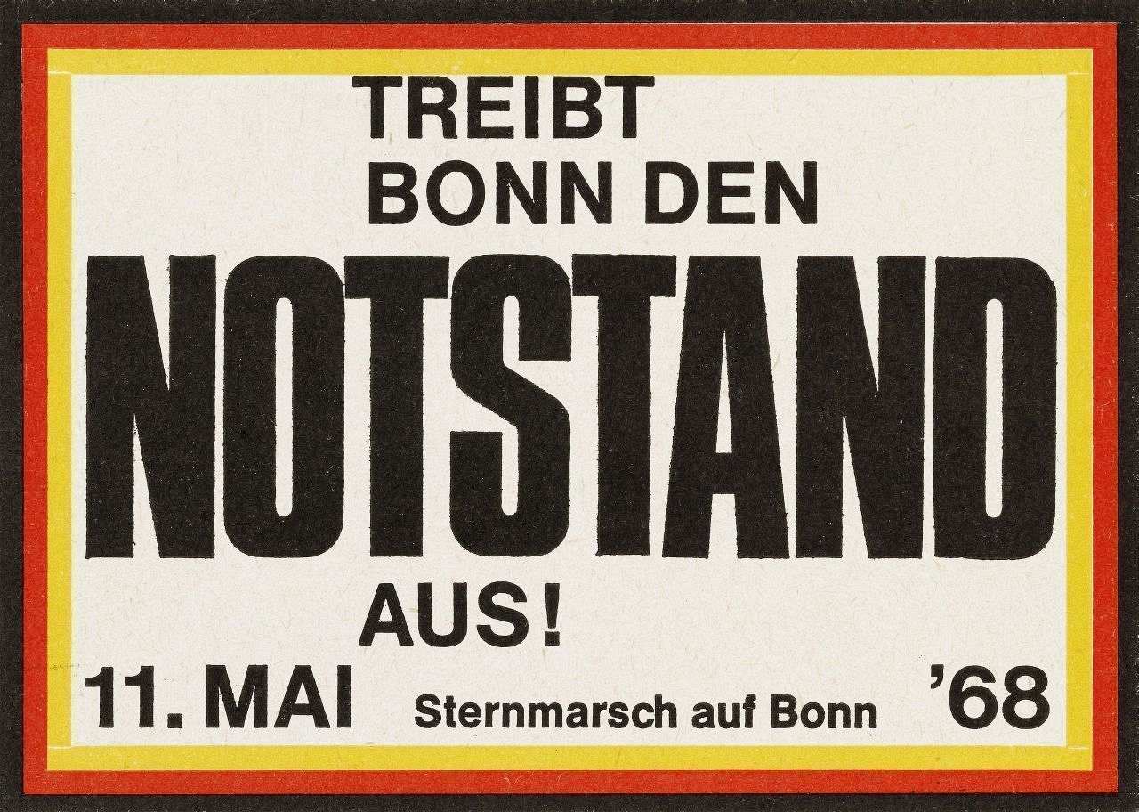Weißer Aufkleber mit schwarz-rot-goldener Umrandung und schwarzer Schrift: Treibt Bonn den Notstand aus! Sternmarsch auf Bonn am 11.5.1968.