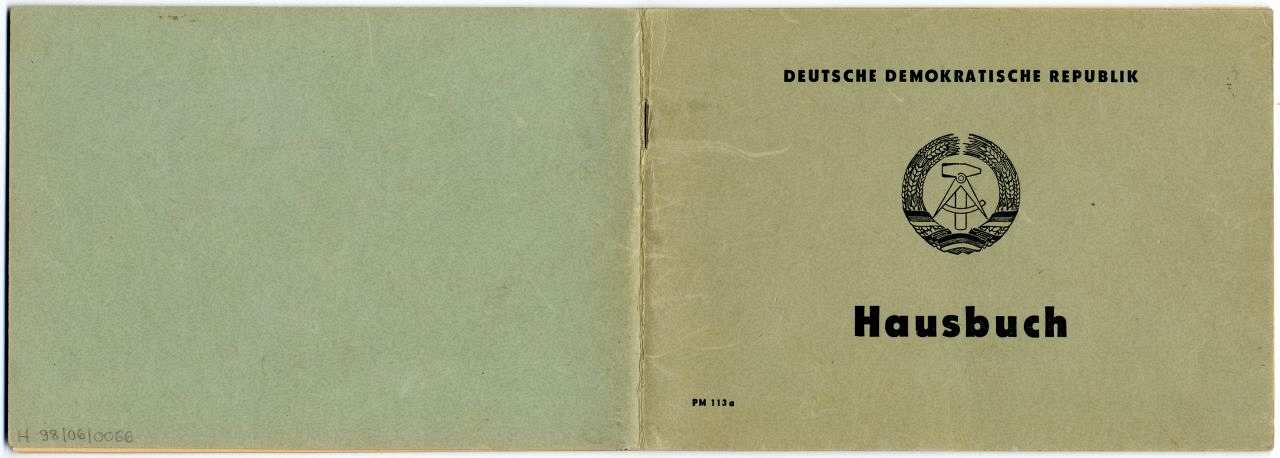 Außenseite des Hausbuches. Grün-grauer Einband, auf der Vorderseite das Staatswappens der DDR: Hammer und Sichel, umgeben von einem ein Ährenkranz mit deutscher Fahne. Darüber die Aufschrift Deutsche Demokratische Republik, darunter die Aufschrift Hausbuch.