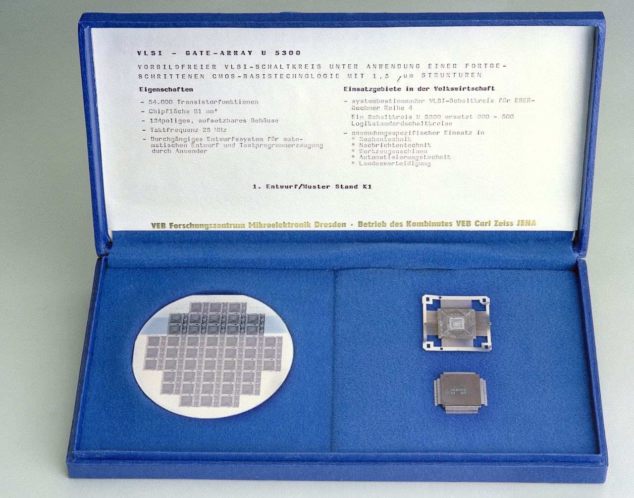 Blauer Hartpappe-Karten mit Deckel und blauem Innenpolster. Im Deckel: Angaben zu VLSI-GATE-ARRAY U 5300. Auf Polster: Siliciumscheibe mit Chips; 2 Fertigungsstufen des elektronischen Bauteils. Typenaufdruck auf Chip: U 5301 FC - V 9 101  (V=1987, 9=September).