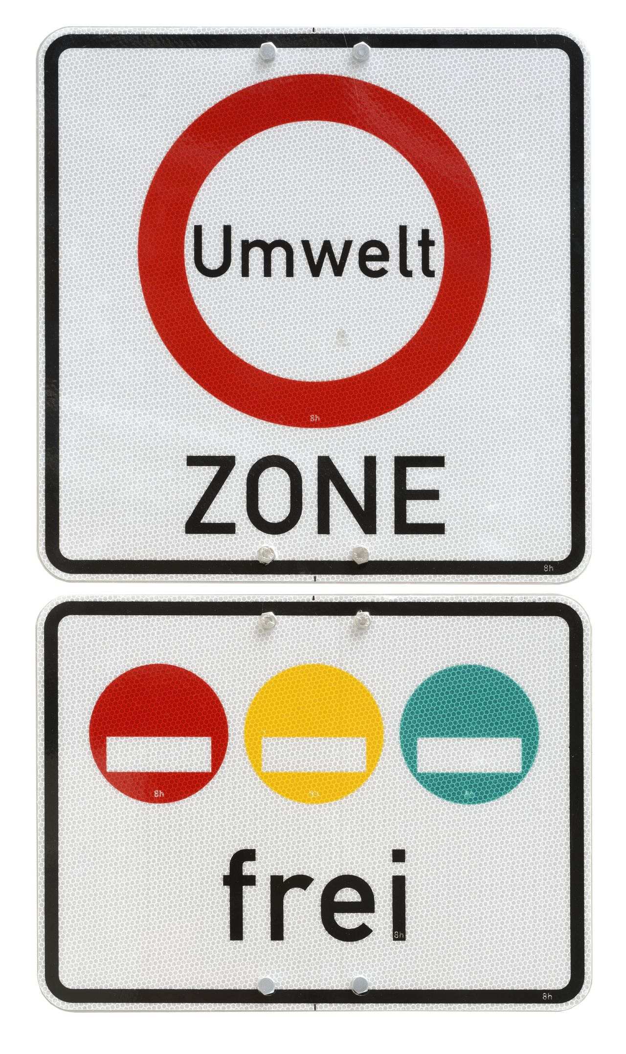 Zwei auf der Rückseite mit Halteplatte festverschraubte rechteckige, an den Kanten abgerundete Schilder. Oberes Umweltzonen-Schild bestehend aus zwei einzelnen Schildern. Oberes Schild: Oben und unten zwei Lochungen. In den unteren Lochungen jeweils eine Schraube. Weiße Grundfarbe, schwarze Umrandung. Mittig zentriert roter Kreis, Text im Kreis mit schwarzer Schrift: Umwelt. Darunter in schwarzer Schrift: Zone. Unteres Schild: Oben und unten zwei Lochungen. In den oberen Lochungen jeweils eine Schraube. Weiße Grundfarbe, schwarze Umrandung. Oberer Teil nebeneinander je ein roter, gelber und grüner vollflächiger Kreis mit einer rechteckigen Aussparung, darunter in schwarzer Schrift: frei.