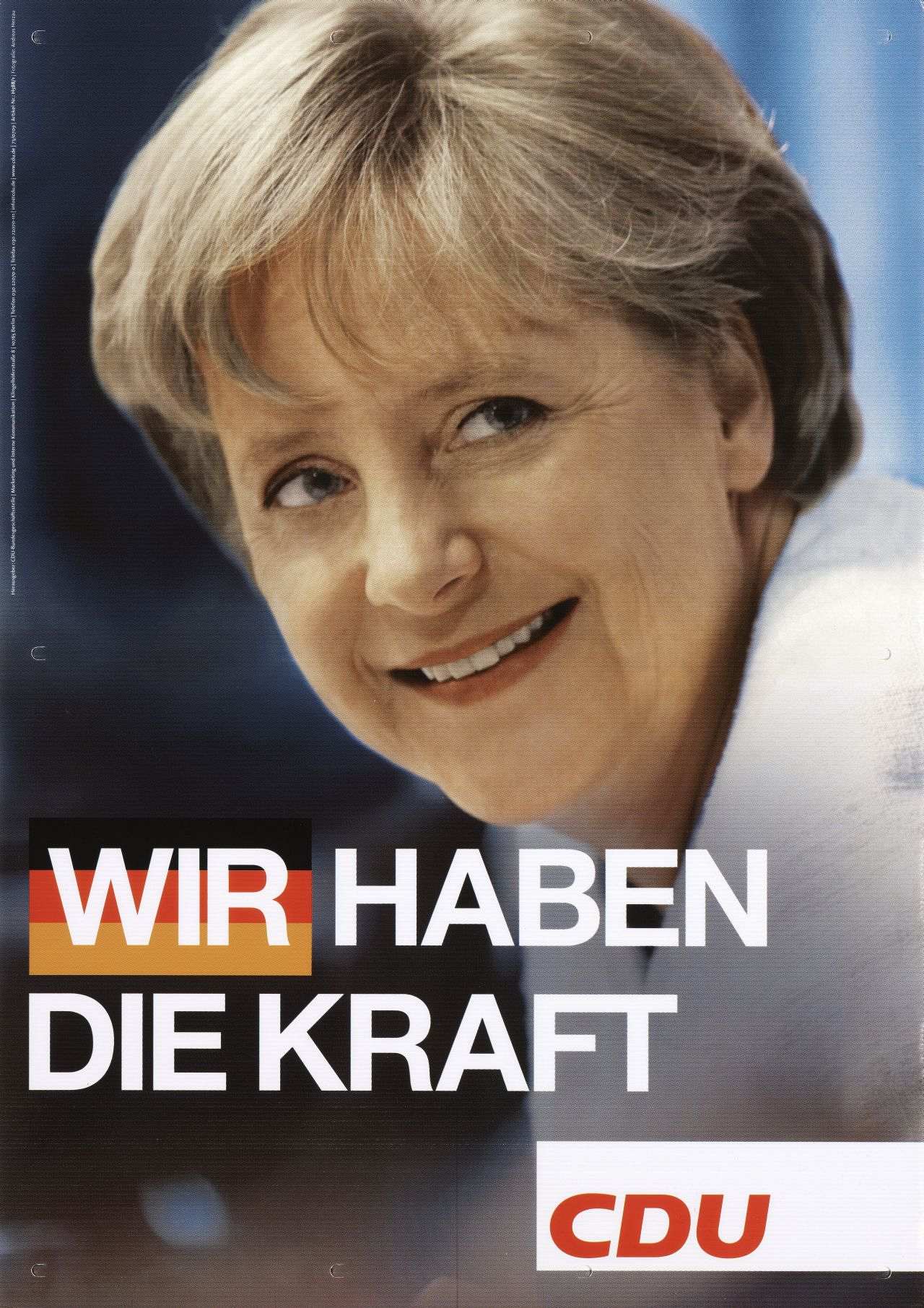 Auf Pappe aufgezogenes, farbiges Plakat; Motiv: Farbfotografie: Angela Merkel, lächelnd; bis zu den Schultern sichtbar; unten, in weißen Großbuchstaben: Wir haben die Kraft; wir in schwarz-rot-goldenem Feld; darunter, rechts: weißes Feld mit Logo CDU; an den Rändern: vorgestanzte Löcher zum Aufhängen des Plakates.