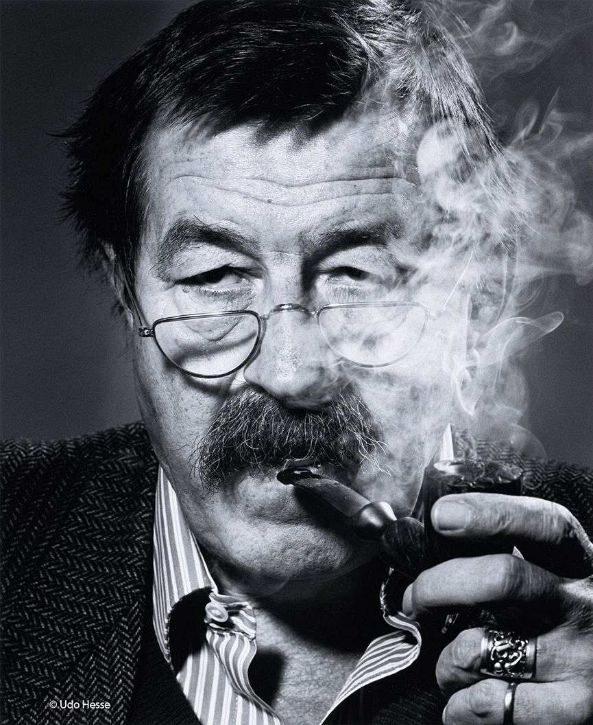 Günter Grass mit Lesebrille, in der linken Hand die brennende Pfeife vor dem Mund haltend