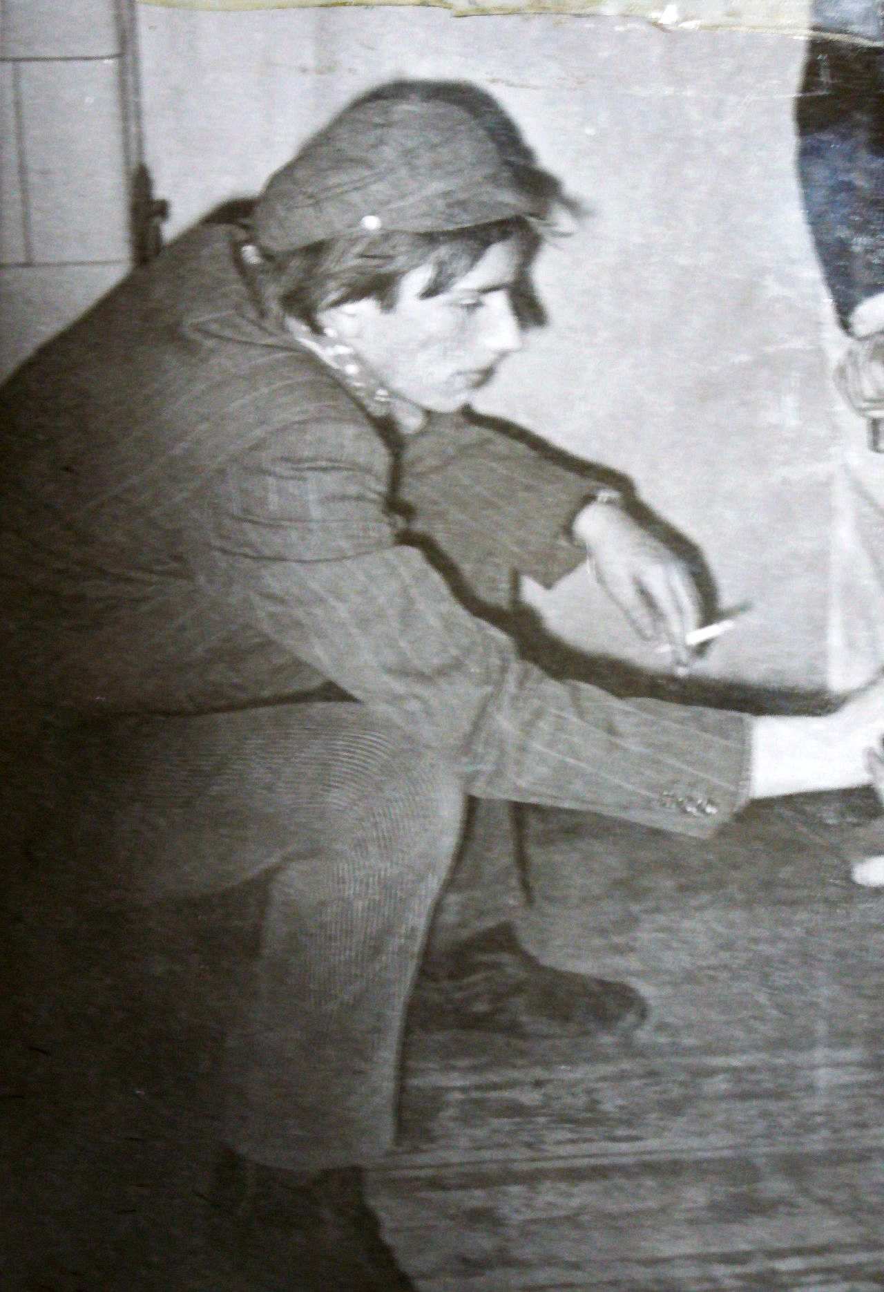 Ein junger Mann im Nadelstreifen-Jacket mit Kappe raucht Zigarette.