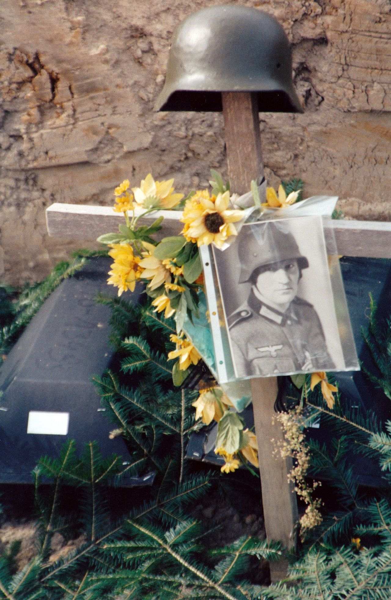 Nachdem LeMO-Zeitzeuge Alfred Keffel die sterblichen Überreste seines im zweiten Weltkrieg gefallenen Vaters Alfred Harry Keffel gefunden hat, kann er ihn am 24. September 2003 auf dem deutschen Soldatenfriedhof Pulawy in Polen begraben. Auf der Fotografie ist eine Detailaufnahme des Sarges mit einem Holzkreuz und einer Fotografie seines Vaters zu sehen. 