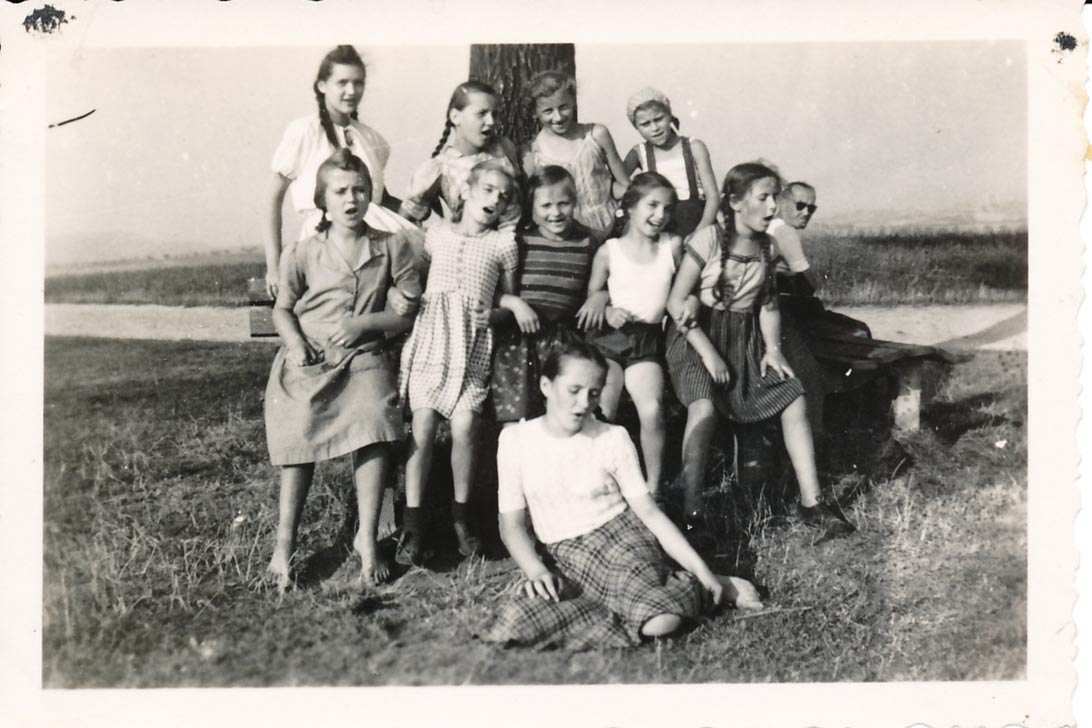 Diese schwarz-weiß-Fotografie zeigt die Zeitzeugin Sigrid Otto, die als Lehrerin in der DDR arbeitet, bei einer Rast nach einem Feldeinsatz mit Mädchen des 7. Schuljahres 1951.