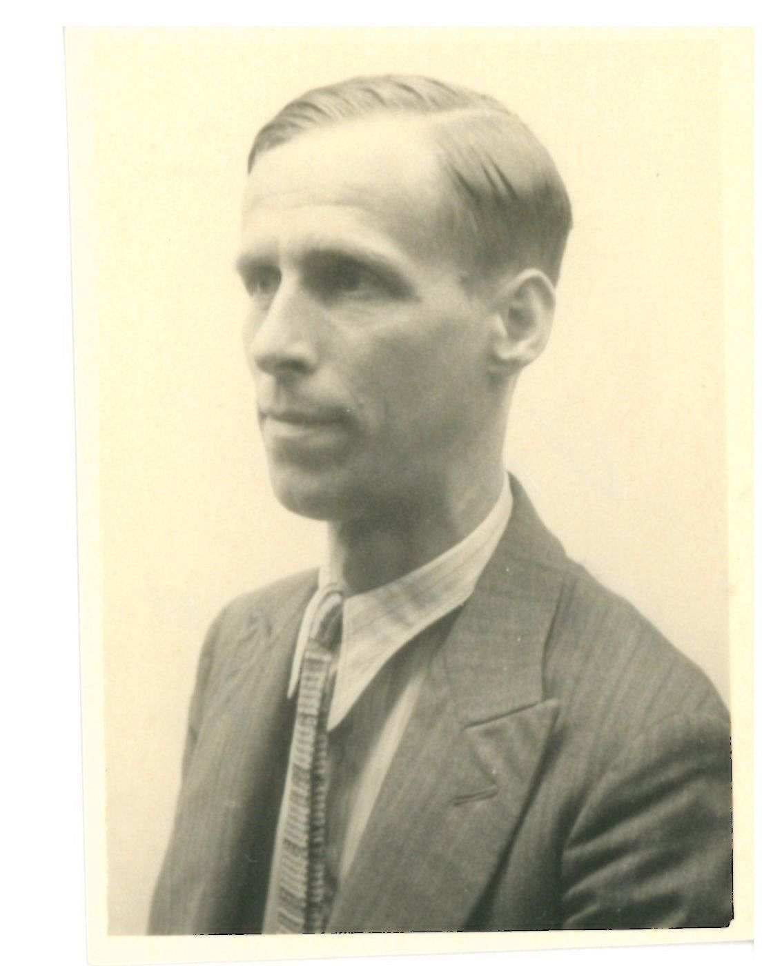 Hochkantfoto, schwarz-weiß Fotografie, Porträt von der Seite, ein ca. 30 bis 40 Jahre alter Mannes im Anzug mit Krawatte und strenger Frisur mit Seitenscheitel