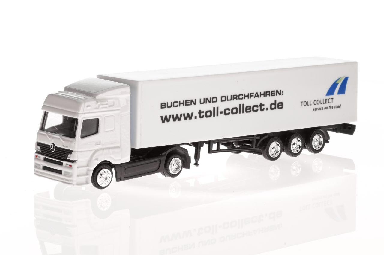 Weißer Spielzeug-Mercedes-LKW mit schwarzer Aufschrift: Buchen und Durchfahren: / www.toll-collect.de,  blau-grünes Symbol mit der Schrift: Toll collect / service on the road.