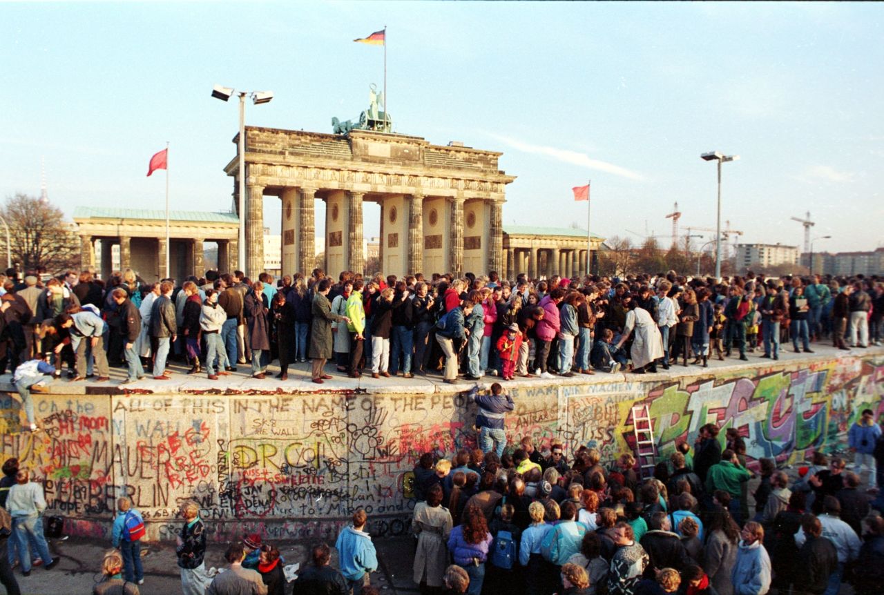 Menschen besteigen die Berliner Mauer vor dem Brandenburger Tor am 10. November 1989.