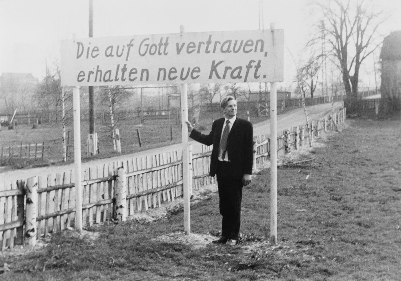 Fotografie des Pfarrers Oskar Brüsewitz mit einem Transparent. Auf diesem ist zu lesen: Die auf Gott vertrauen, erhalten neue Kraft.