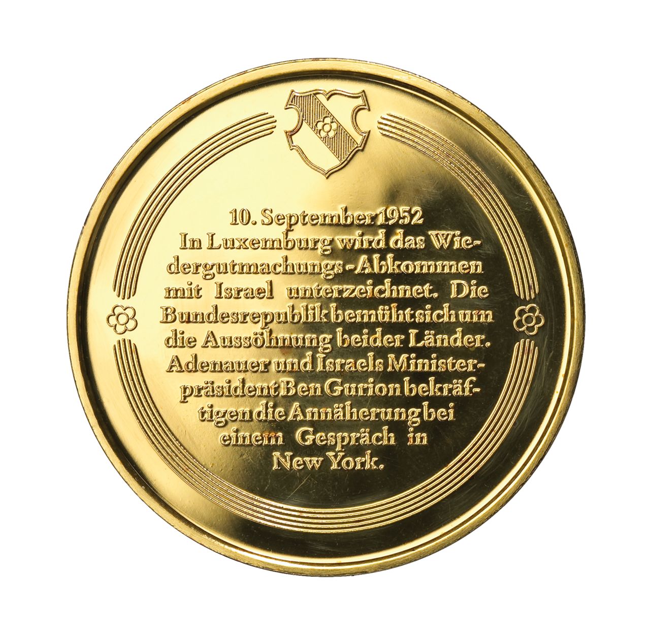 Vergoldete Medaille; Vorderseite: Ben Gurion und Adenauer, freundschaftlich im Gespräch an einem kleinen Tisch sitzend; Umschrift: 'Wiedergutmachung und Aussöhnung mit Israel'. Rückseite: erhabener Text: '10. September 1952 / In Luxemburg wird das Wiedergutmachungsabkommen mit Israel unterzeichnet. Die Bundesrepublik bemüht sich um die Aussöhnung beider Länder. Adenauer und Israels Ministerpräsident Ben Gurion bekräftigen die Annäherung bei einem Gespräch in New York.'