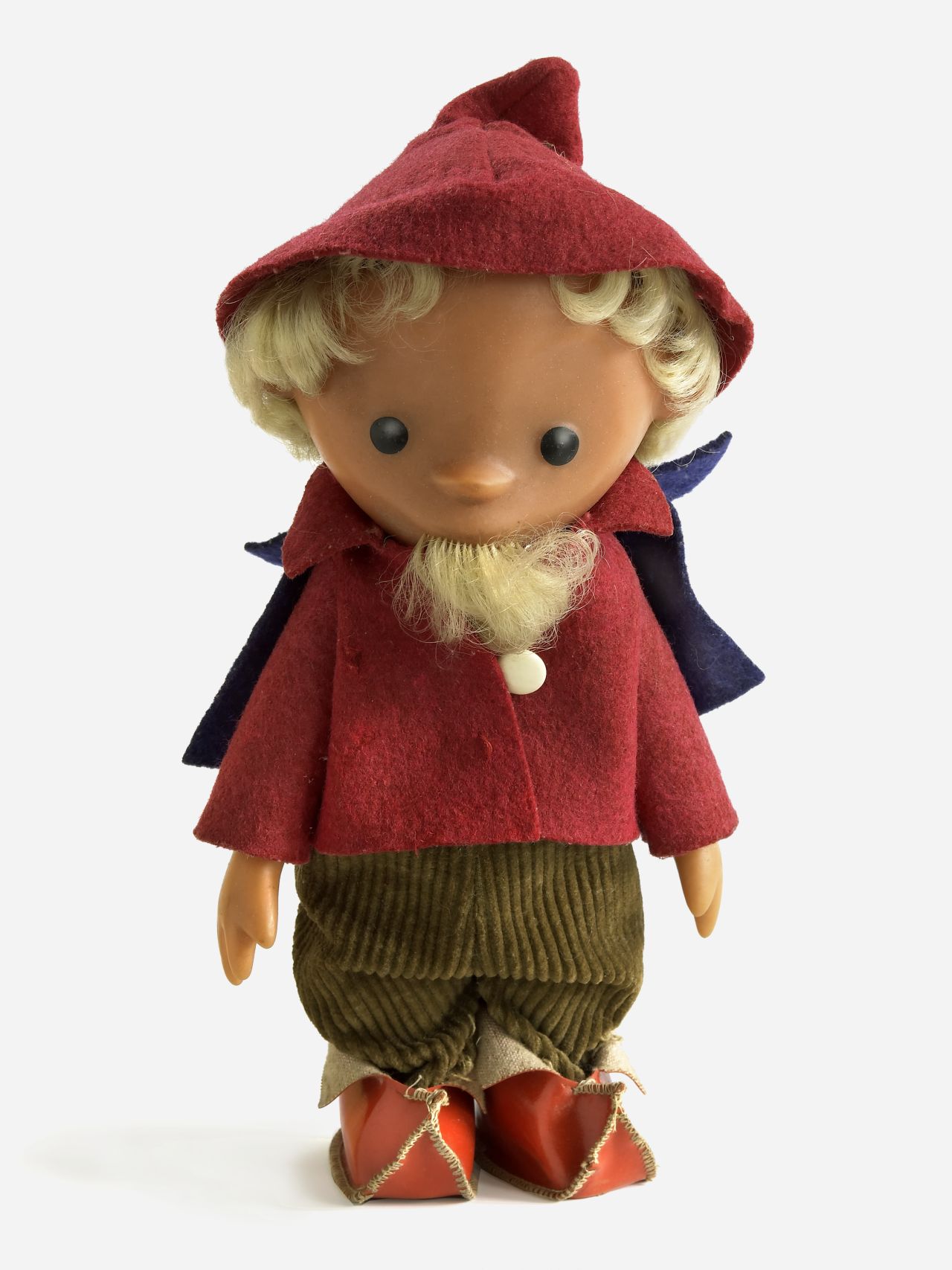 Sandmännchen-Puppe mit rotem Hut, Jacke und Schuhen sowie lila Umhang und grüner Cordhose.