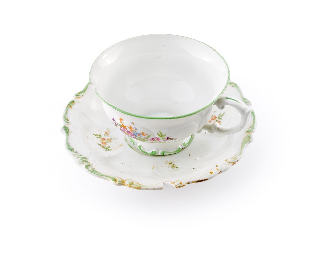 Weiße Tasse und Untertasse mit grünen Rändern aus Prozellan. Auf der Tasse ist ein buntes Blumenbouquet abgebildet. Tassenhenkel und der Rand der Untertasse habe eine geschnörkelte Form.
