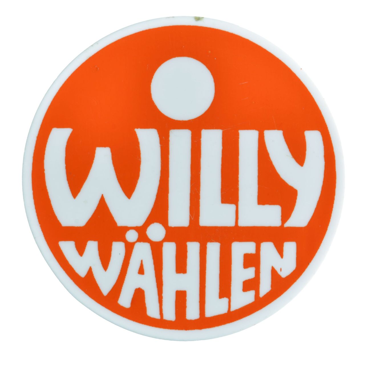 Weißfarbener runder Button mit rotem Kreis und weißer Innenschrift: Willy wählen. Befestigungsnadel auf der Rückseite.
