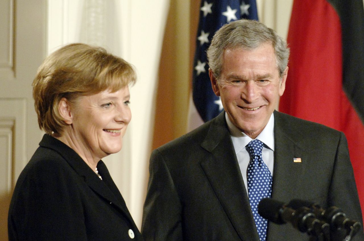 Farbfoto; Angela Merkel und George W. Bush stehend vor Mikrofonen. Im Hintergrund sind Teile der amerikanischen und deutschen Flagge zu sehen.