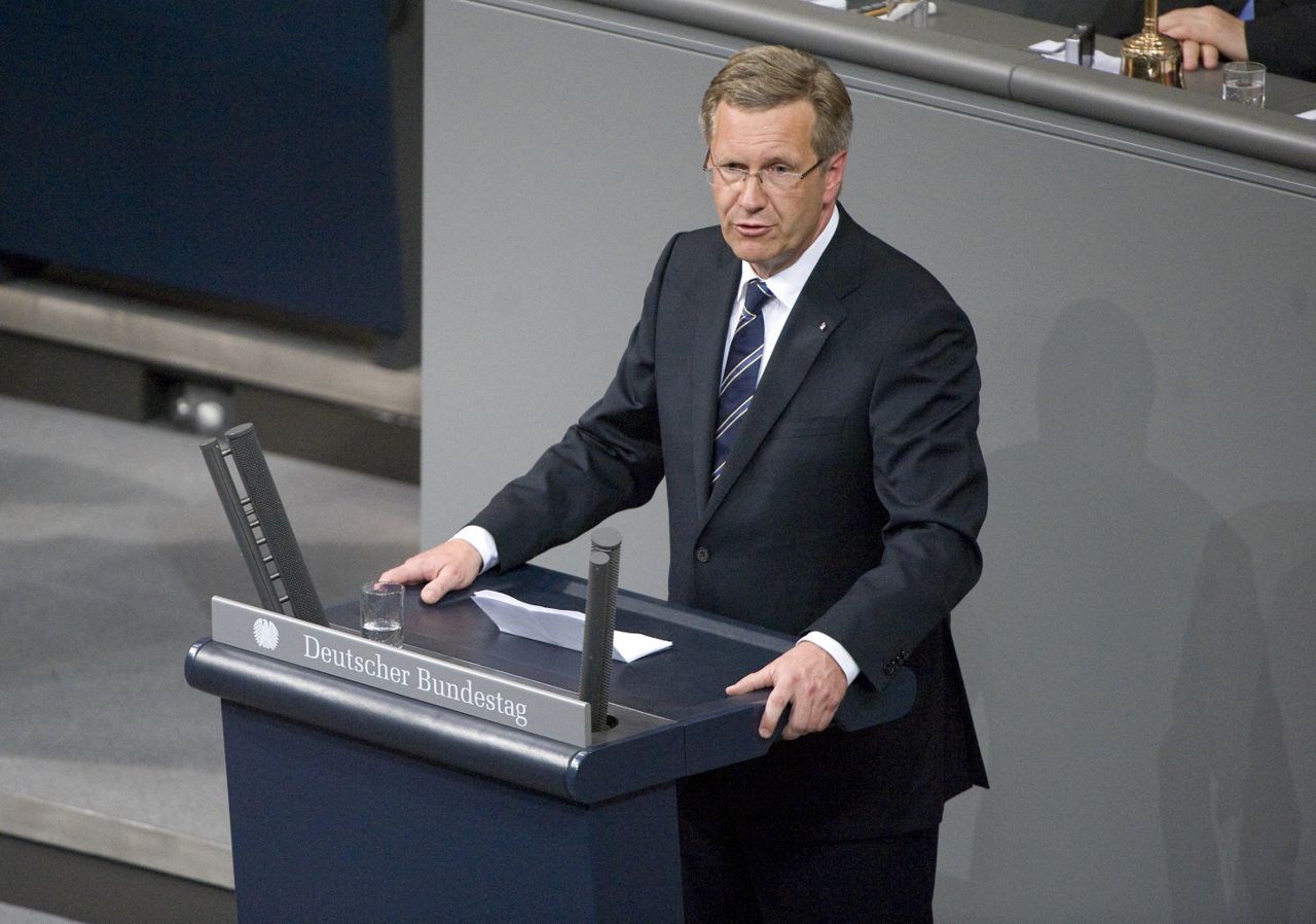 Christian Wulff hält eine Rede stehend hinter einem Rednerpult im Plenarsaal des Bundestages. Er umfasst dabei mit beiden Händen das Pult.