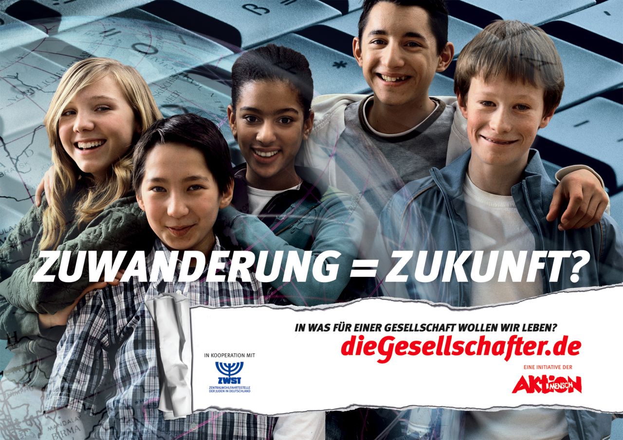 Einseitig bedrucktes, farbiges Plakat, Motiv: locker in die Kamera posierende Gruppe Jugendlicher verschiedener Hautfarbe, die Arme gegenseitig auf den Schultern abgelegt, im Hintergrund übergroße stilisierte Weltkugel mit Gitternetz, sowie Computertastatur. Mittig weiße Aufschrift, fett gedruckt: Zuwanderung = Zukunft? / In was für einer Gesellschaft wollen wir leben? Unten links in roter und blauer Schrift auf weißem Grund Angabe der Herausgeber; rechts Angabe zum Projekt: Werden Sie aktiver Gesellschafter. / Diskussionen, Infos und Projekte unter: / die Gesellschafter.de. Übergang zwischen Bild und weiß grundierter Fläche als Papierriss stilisiert.