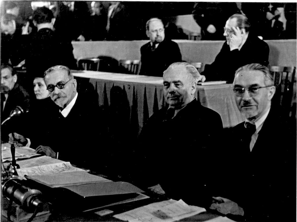 Schwarzweißfoto; 2 lange Tische hintereinander. Jeweils von links gesehen sitzen am vorderen Tisch Wilhelm Külz (LDPD), Wilhelm Pieck (SED), Otto Nuschke (CDU) und am Hinteren Walter Ulbricht (SED) und Otto Grotewohl (SED). Im Hintergrund weitere Personen.