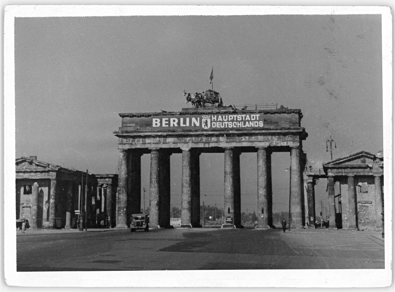 Beschädigtes Brandenburger Tor mit Aufschrift: Berlin Hauptstadt Deutschlands